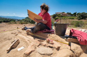 Une archéologue réalise le relevé d'une couverture en suspens (dalle de sol en terre cuite)